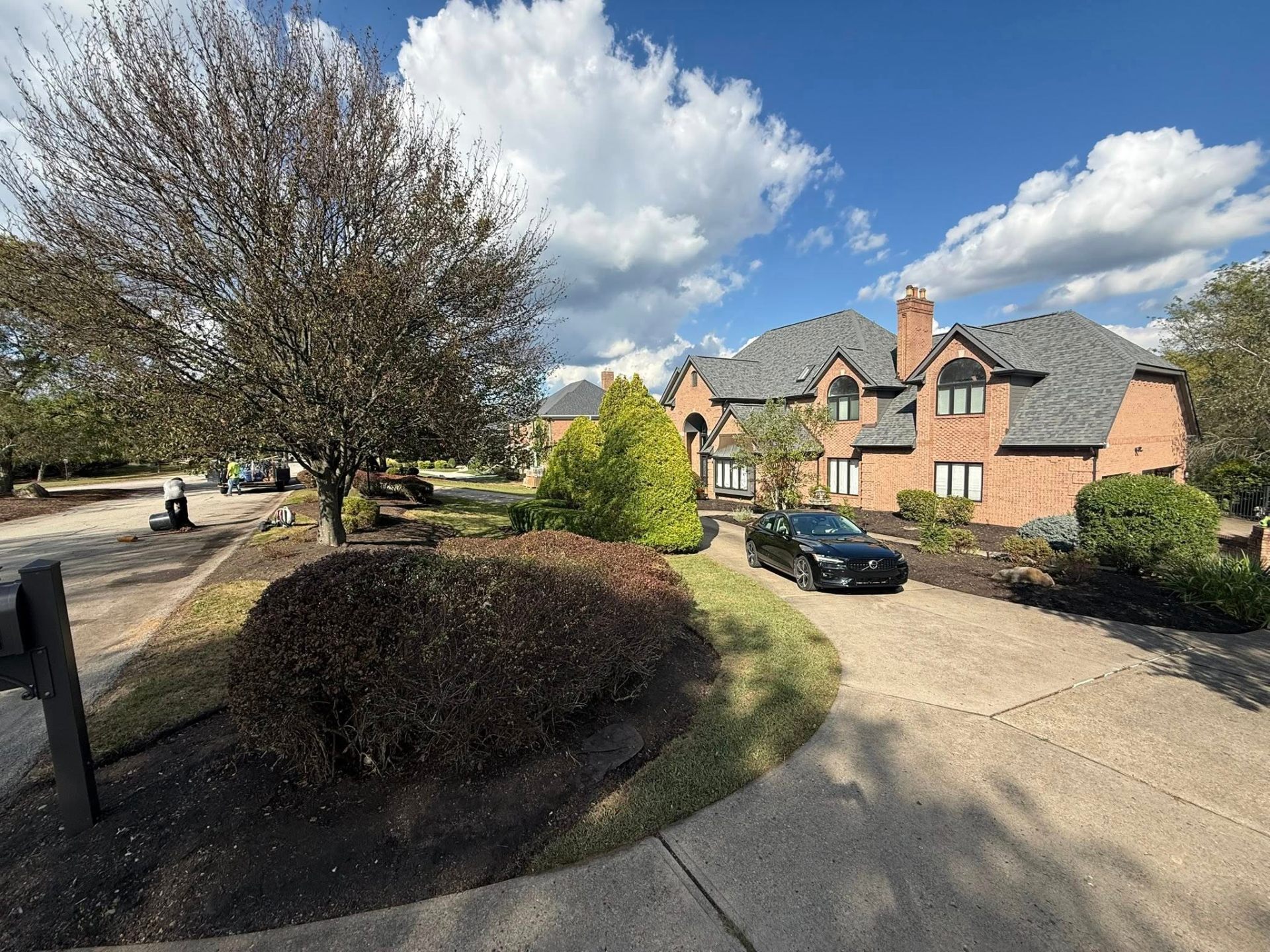 Estate home with manicured shrubs and fresh mulch beds along the driveway
