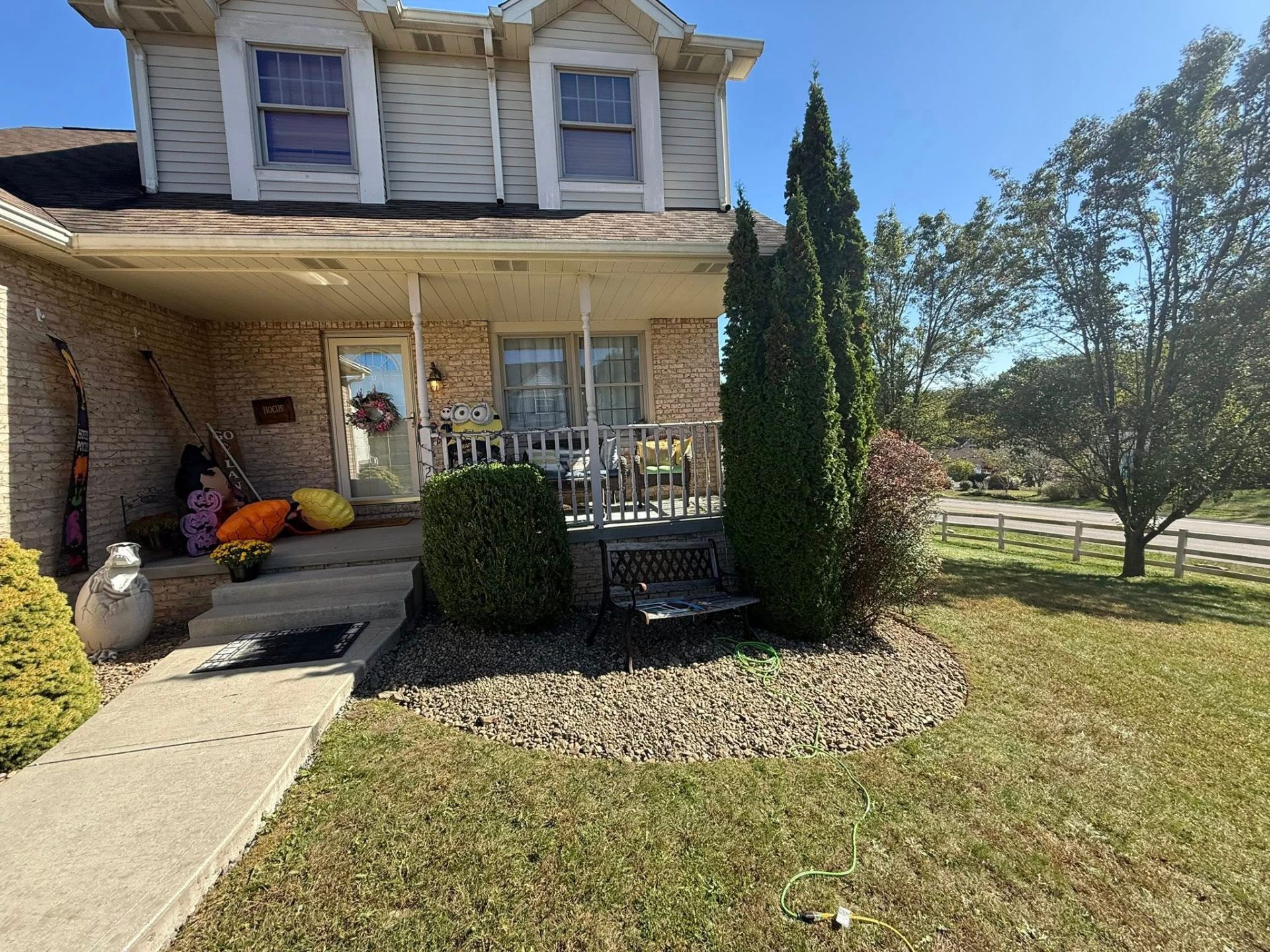 Front porch landscape bed with shaped shrubs and river rock